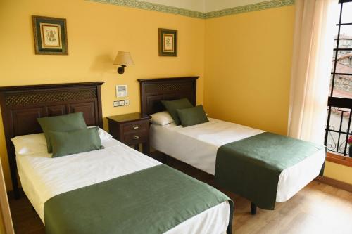 two beds in a room with yellow walls at Hotel Rural Villa de Vinuesa in Vinuesa