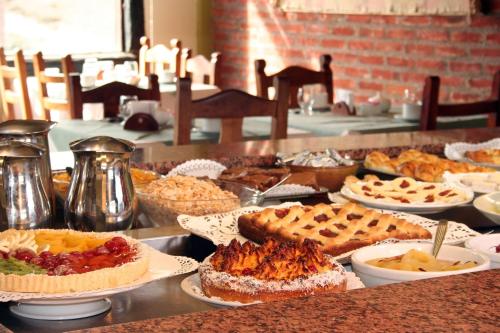 Hosteria Posta Sur في إل كالافاتي: بوفيه مع فطائر وغيرها من الحلويات على الطاولة