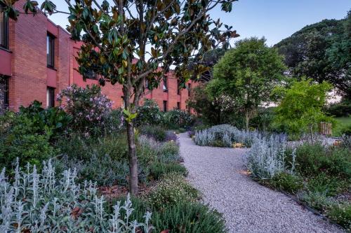 a garden in front of a red brick building at Hotel Eden Park by Brava Hoteles in Riudellots de la Selva