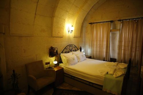 a bedroom with a bed and a chair and a window at Castle Inn Cappadocia in Ürgüp