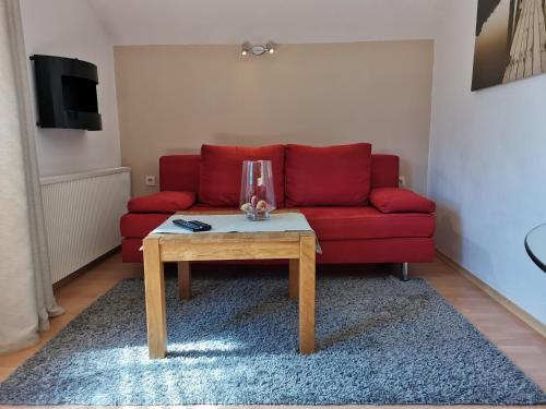 a red couch with a coffee table in a living room at Yimi Ferienwohnung in Grafenwiesen