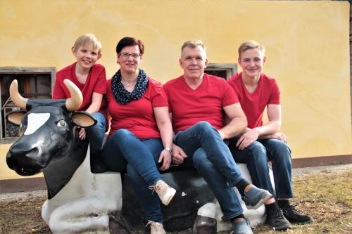 un grupo de personas sentadas sobre una estatua de vaca en Erlebnisbauernhof Urak, en Sankt Kanzian