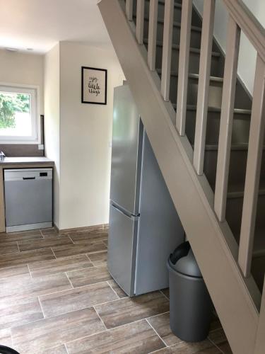a kitchen with a refrigerator and a staircase at Gîte T'ché Dédée in La Cambe