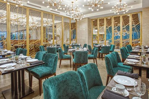 a restaurant with green chairs and tables and chandeliers at Kingsford Hotel Manila Bay in Manila