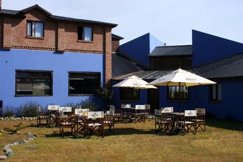 a group of tables and umbrellas in front of a building at Hosteria Posta Sur in El Calafate