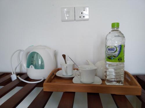 a bottle of water sitting on a wooden tray with cups at Holly House Homestay in Ella