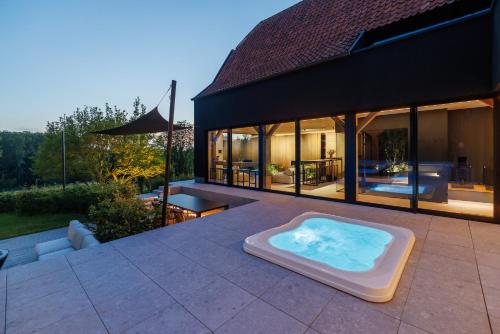 un bain à remous sur une terrasse avec une maison dans l'établissement Holiday Home L'O Reine - with luxury wellness, à Sint-Pieters-Leeuw