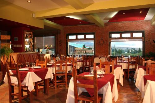 a dining room with tables and chairs and windows at Hosteria Posta Sur in El Calafate