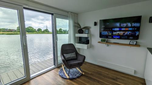 une chaise noire dans une chambre avec une grande fenêtre dans l'établissement Hausboot Wangermeerblick (Floating Home), à Wangerland