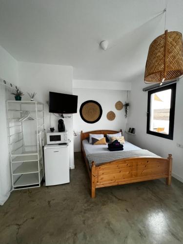 um quarto com uma cama, um micro-ondas e uma televisão em Casa Nusa em La Santa