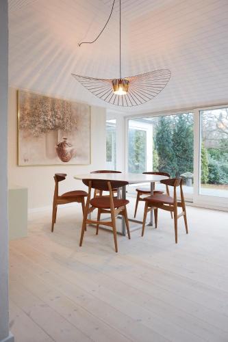 a dining room with tables and chairs and a chandelier at Gilleleje Badehotel in Gilleleje