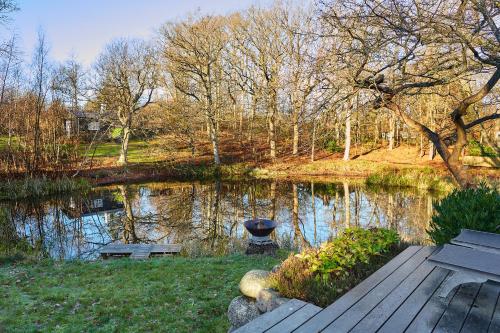 a park with a pond with a bench and trees at Gilleleje Badehotel in Gilleleje