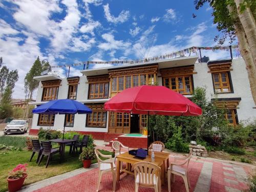 tavolo e sedie con ombrelloni di fronte a una casa di Jig Gyas Guest House a Leh