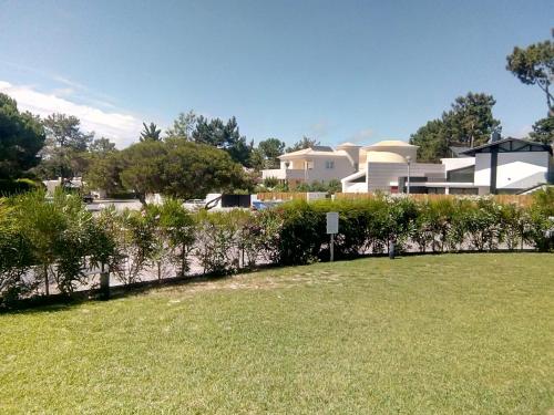 a fence with bushes in front of a house at Casa das Dunas Soltroia in Troia