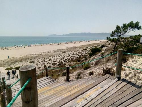 a boardwalk leading to a beach with a lot of people at Casa das Dunas Soltroia in Troia