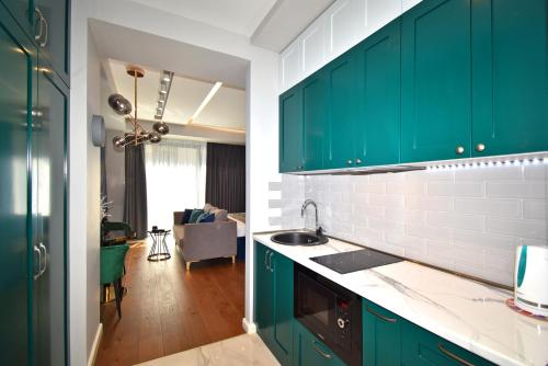 a kitchen with green cabinets and a living room at Yerevan4you NEW Studio Apartment in Yerevan
