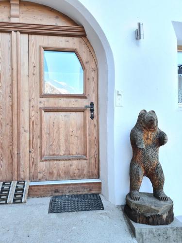 Una statua di un orso che si trova davanti a una porta di Lumpaz a Santa Maria Val Müstair