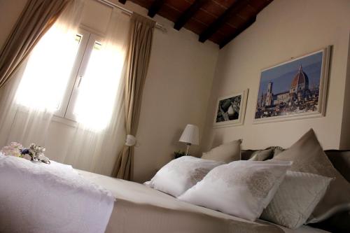 a bedroom with a bed with white pillows and a window at La Torre di Anna in Florence
