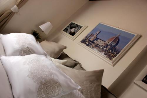 a bedroom with a bed with white pillows and pictures at La Torre di Anna in Florence