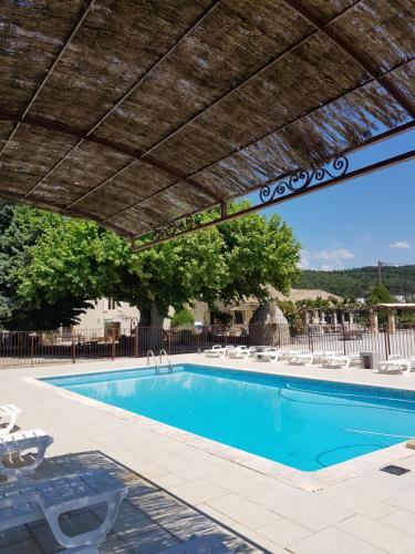 - une piscine avec un parasol et des chaises en bois dans l'établissement Chambres & Tables d'hôtes Moulin de Lavon, à Gargas