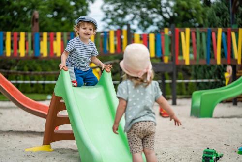 two children playing on a slide at a playground at Pod Dębami Domki ,Pokoje,Nauka jazdy konnej Sarbsk obok Łeby in Sarbsk