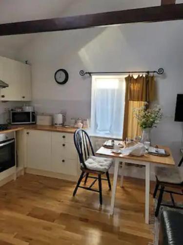 a kitchen with a table and a chair in a room at Birch Cottage with private wood fire hot tub in Harrietsham