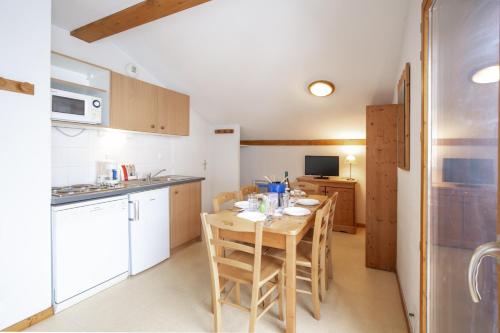 a kitchen with a table and chairs in a room at Les Balcons PROCHE PARC NATIONAL VANOISE appartements 2 pieces 6 pers MONTAGNE in Termignon