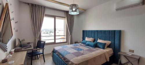 Un dormitorio con una cama y un escritorio y una ventana. en Design & luxury apartment with sea view in Mrezga Hammamet, en Nabeul