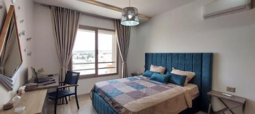 a bedroom with a bed and a desk and a window at Design & luxury apartment with sea view in Mrezga Hammamet in Nabeul