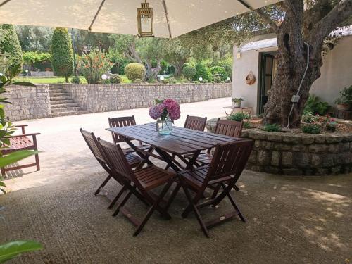 a wooden table with chairs and a vase of flowers at Casa Vacanze Nino Petrelli in Naso