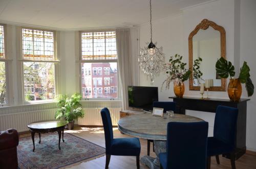 uma sala de estar com uma mesa e cadeiras e uma televisão em Huize Maurits em Haia