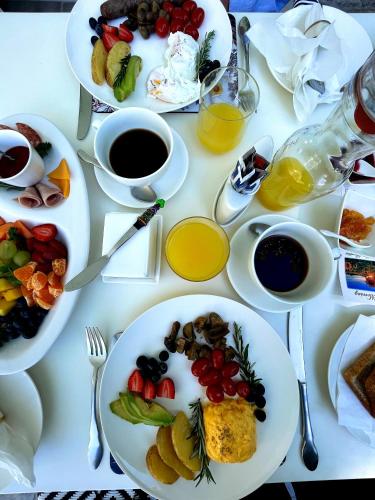a white table with plates of food and cups of coffee at Fleur du Soleil Luxury Guesthouse in Franschhoek