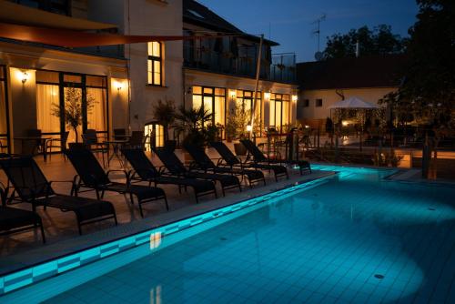 a swimming pool with chairs next to a building at Elizabeth Hotel in Gyula