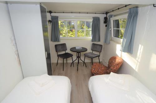 Cette chambre comprend deux lits, une table et des chaises. dans l'établissement Folkshegeskoalle Schylgeralân, à Hoorn