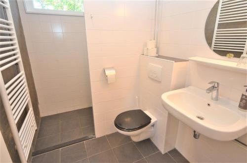 La salle de bains est pourvue de toilettes noires et d'un lavabo. dans l'établissement Folkshegeskoalle Schylgeralân, à Hoorn