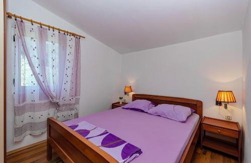 a bedroom with a bed with purple sheets and a window at Apartments Oliver in Putniković