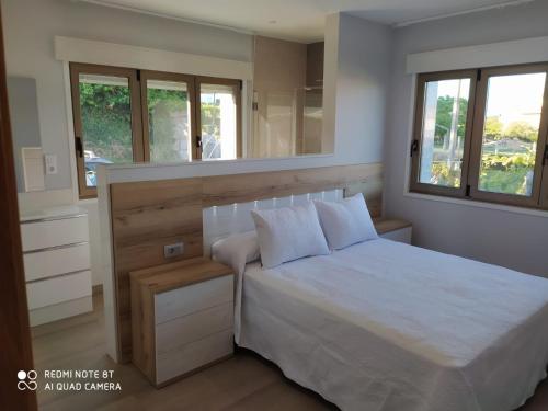 Schlafzimmer mit einem weißen Bett und einem Spiegel in der Unterkunft Casa Surf Lanzada in Sanxenxo