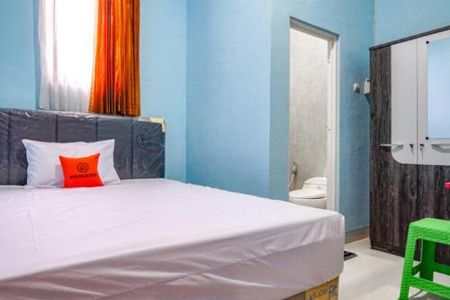 a bedroom with a bed with a red pillow on it at KoolKost Syariah @ Dukuh Kupang (Minimum Stay 30 Nights) in Putat-wetan