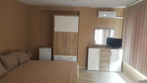 a bedroom with a bed and a dresser with a television at Valemar Apartments in Pomorie