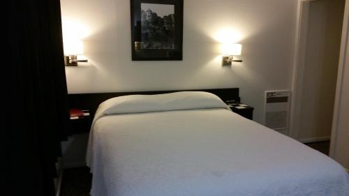 a bedroom with a white bed and two lights on the wall at Rocket Motel in Custer