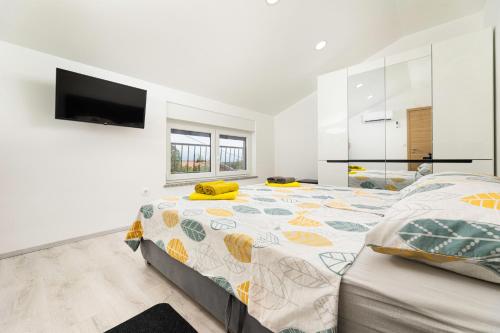 a white bedroom with a bed and a flat screen tv at Villa Veroniq in Županje