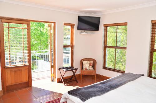 um quarto com uma cama e uma televisão na parede em Penelope's Stellenbosch em Stellenbosch