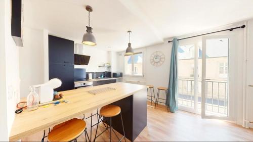 una cucina con bancone, sgabelli e ampia finestra di Superbe appartement au cœur du centre ville a Caen