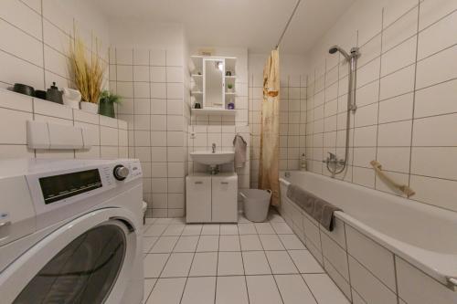 a white tiled bathroom with a washing machine in it at Spreewald-Apartment, 75qm, 2 Schlafzimmer, Tiefgarage, Balkon, Netflix, Waschtrockner in Cottbus
