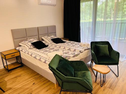 1 dormitorio con 1 cama y 2 sillas verdes en WRZOS resort & wellness **** DOMKI CAŁOROCZNE, en Węgierska Górka