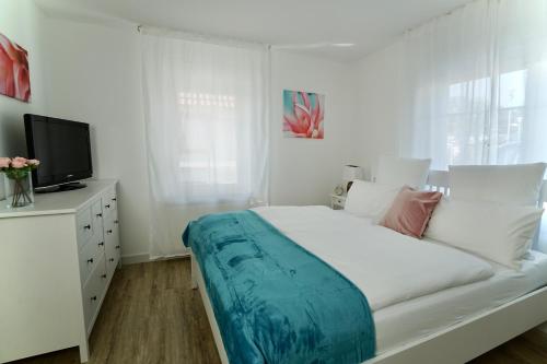 a white bedroom with a large bed and a tv at MyHome Ruegen - Haus Sonnenmeer in Ostseebad Sellin