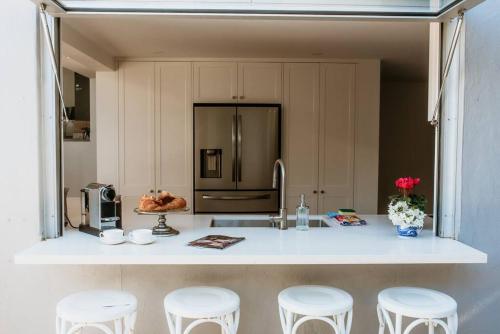 a kitchen with a counter with stools and a refrigerator at Stunning Harbourside Home with Panoramic Views in Sydney