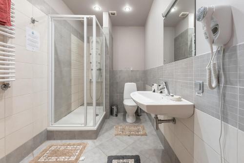 a white bathroom with a shower and a sink at Valensija - Large Suite apartment in Jūrmala