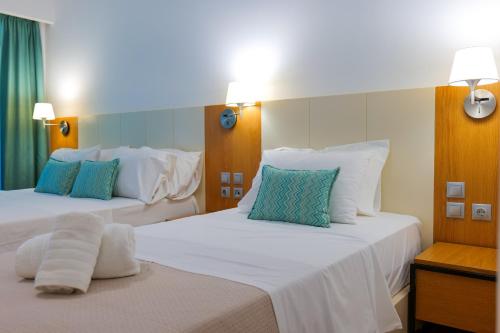 two beds in a hotel room with white and blue pillows at Royal 1967 in Himare