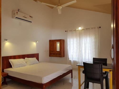 a bedroom with a bed with a desk and a window at Kizhunna rock beach house in Kannur